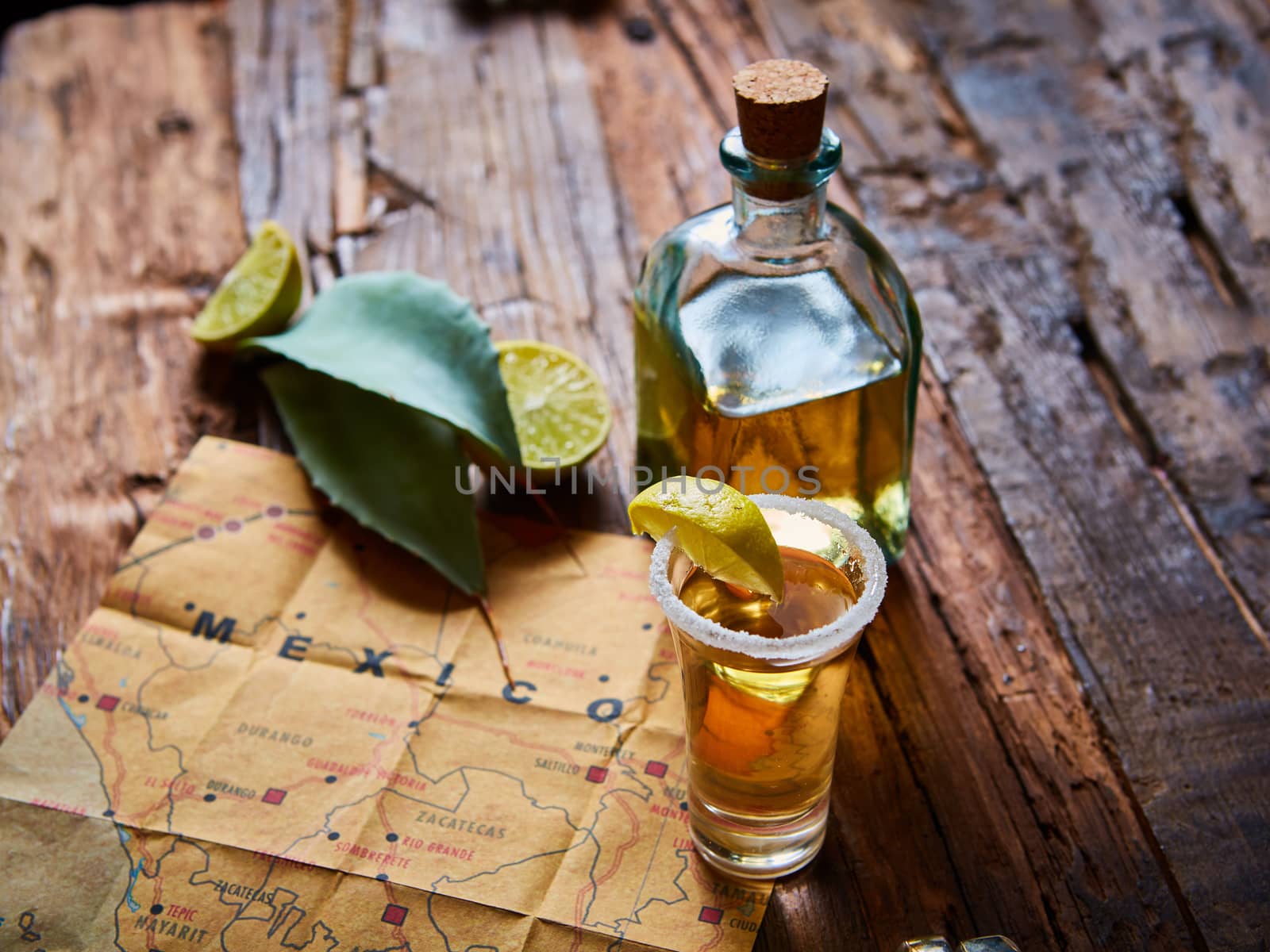 Tequila shot with lime and sea salt on wooden table, selective focus