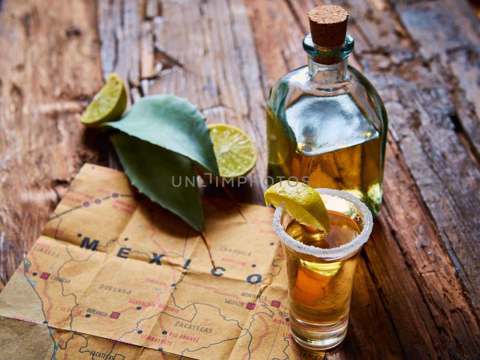 Tequila shot with lime and sea salt on wooden table, selective focus