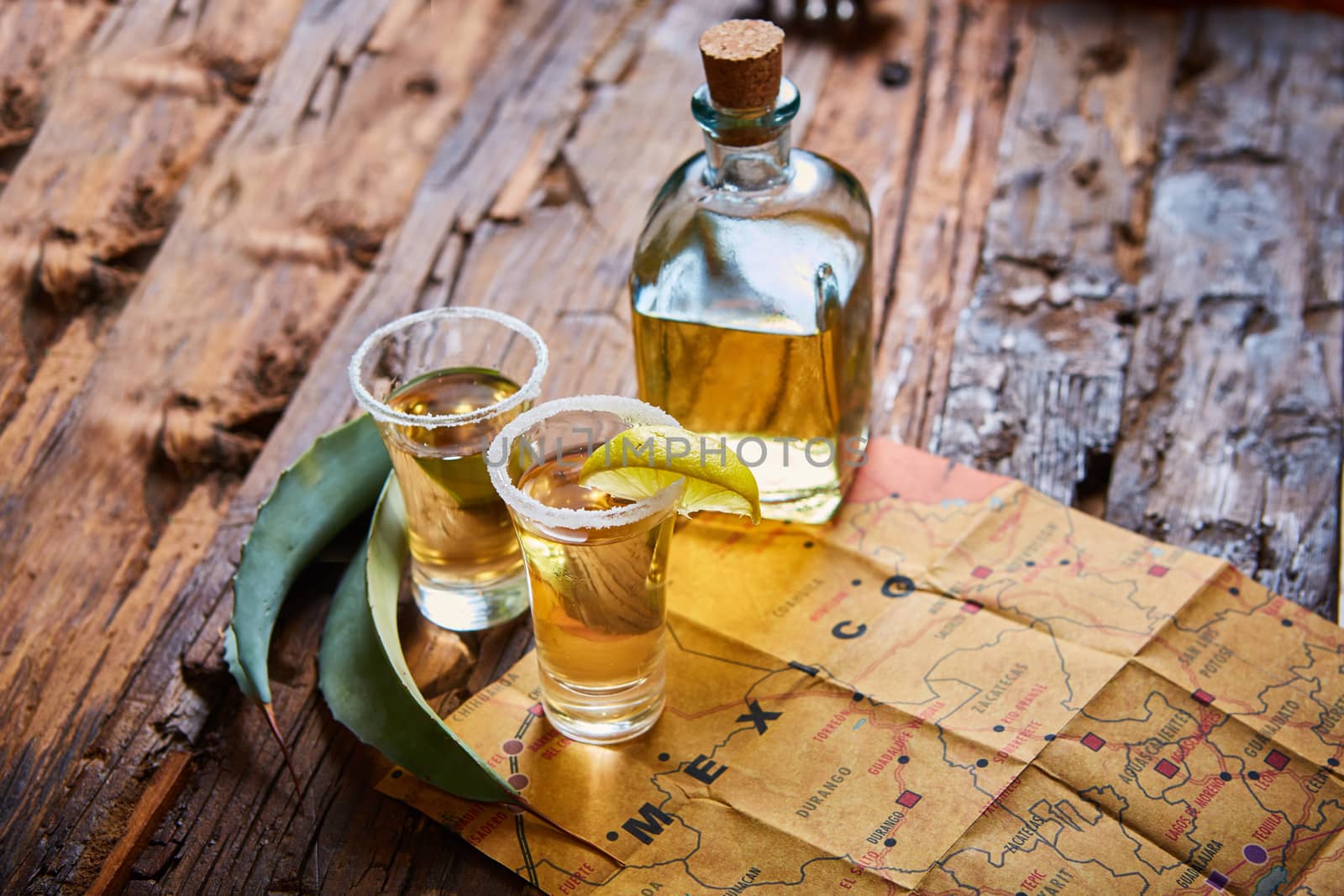 Tequila shot with lime and sea salt on wooden table, selective focus