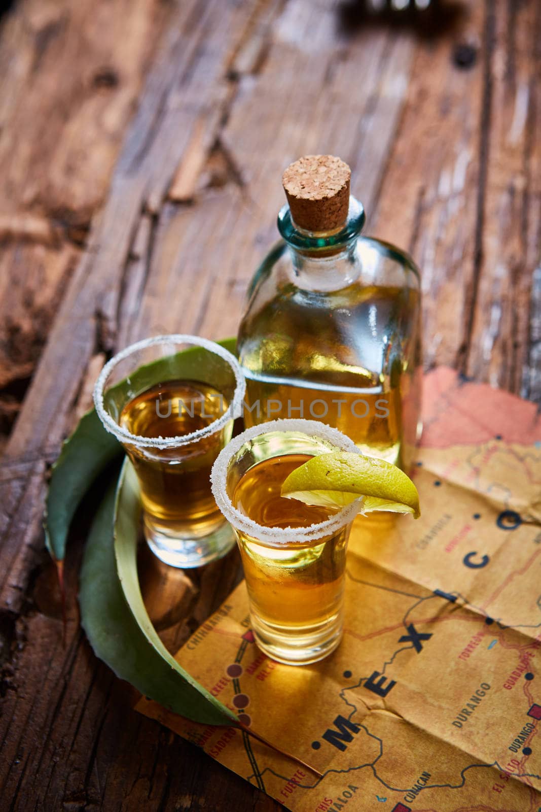 Tequila shot with lime and sea salt on wooden table, selective focus