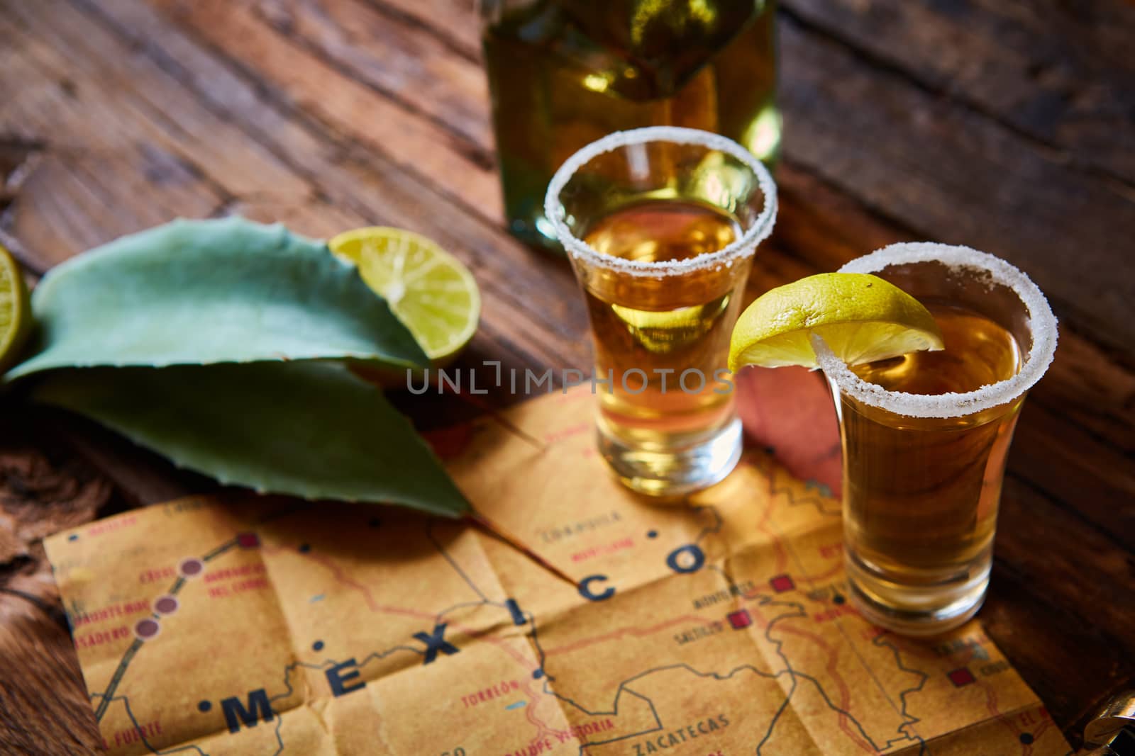 Tequila shot with lime and sea salt on wooden table, selective focus