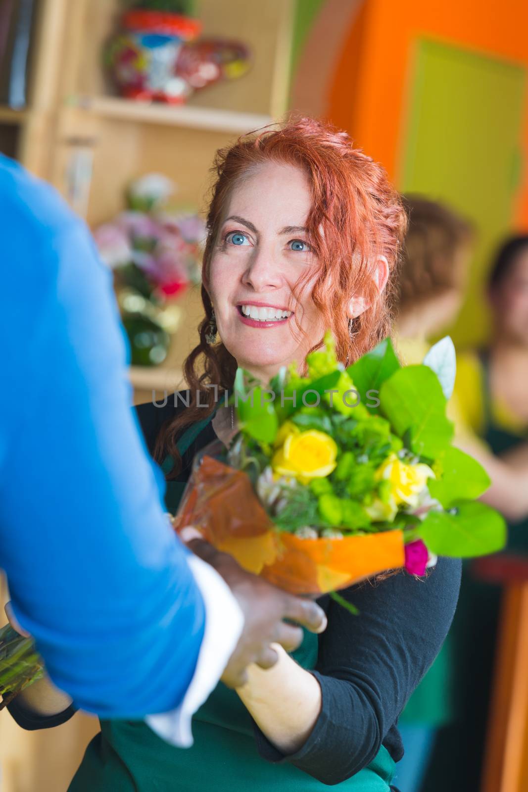 Woman selling bouquet in a busy flower shop