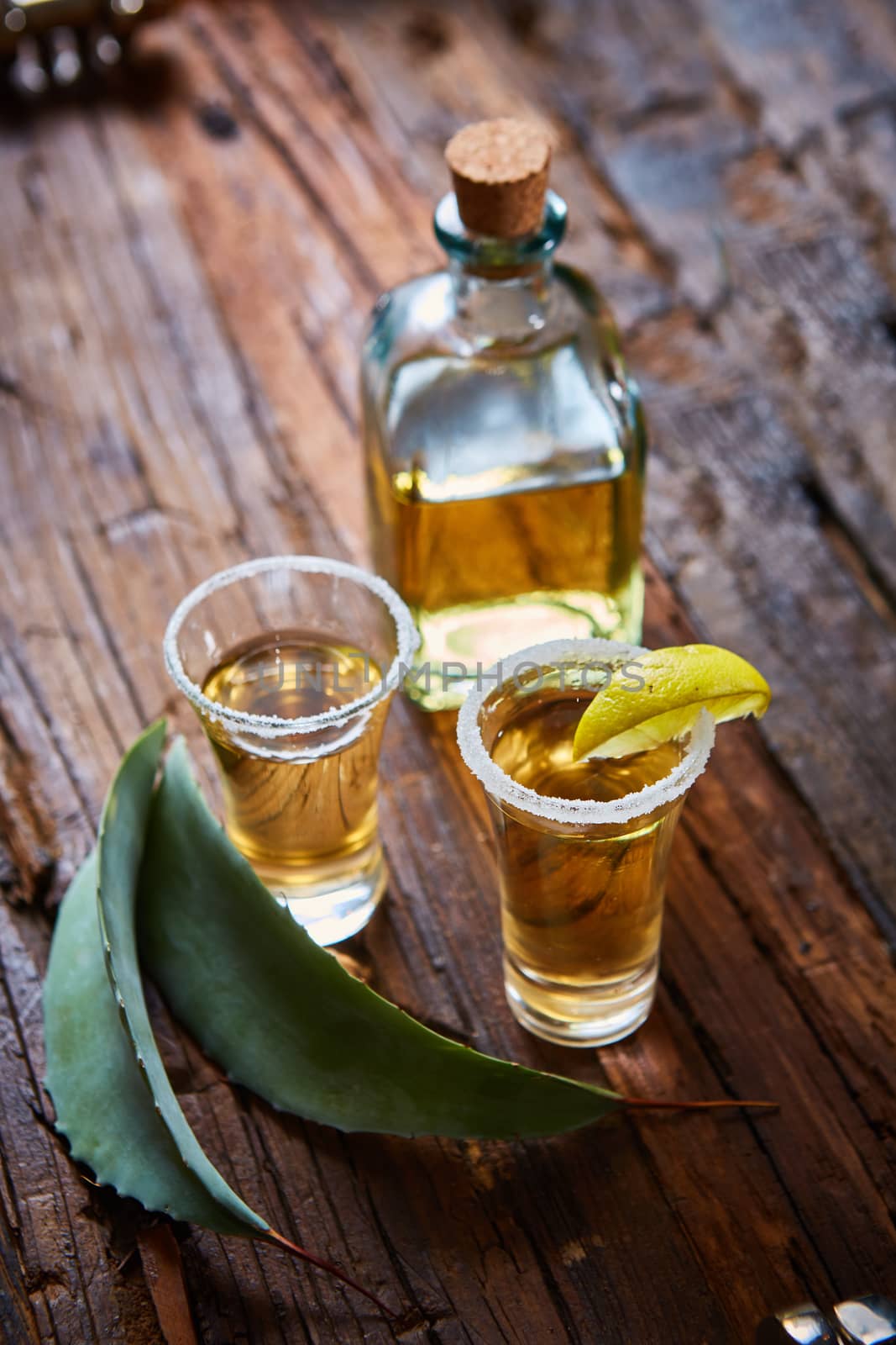 Tequila shot with lime and sea salt on wooden table, selective focus