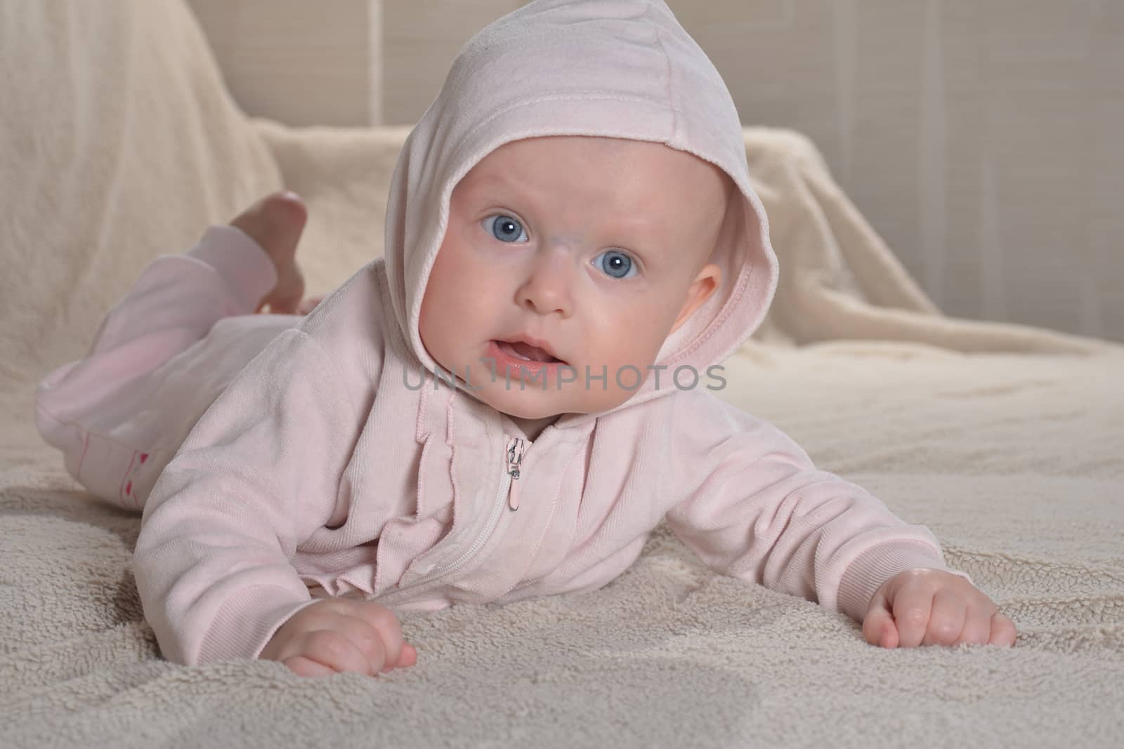 newborn girl wearing pink bathrobe and lying in her bed looking 