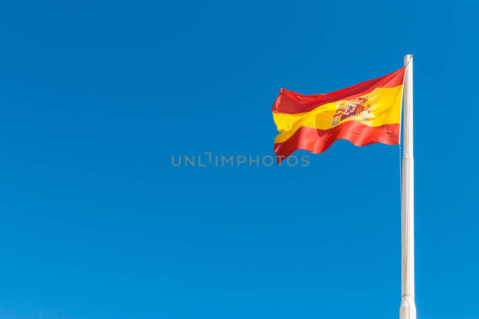 Spanish flag waving in the blue sky. Flag of Spain.