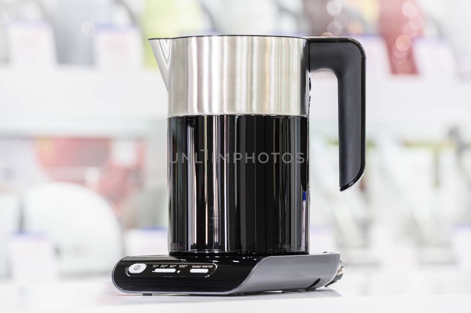 Single brand new premium electric kettle at retail store shelf, defocused background