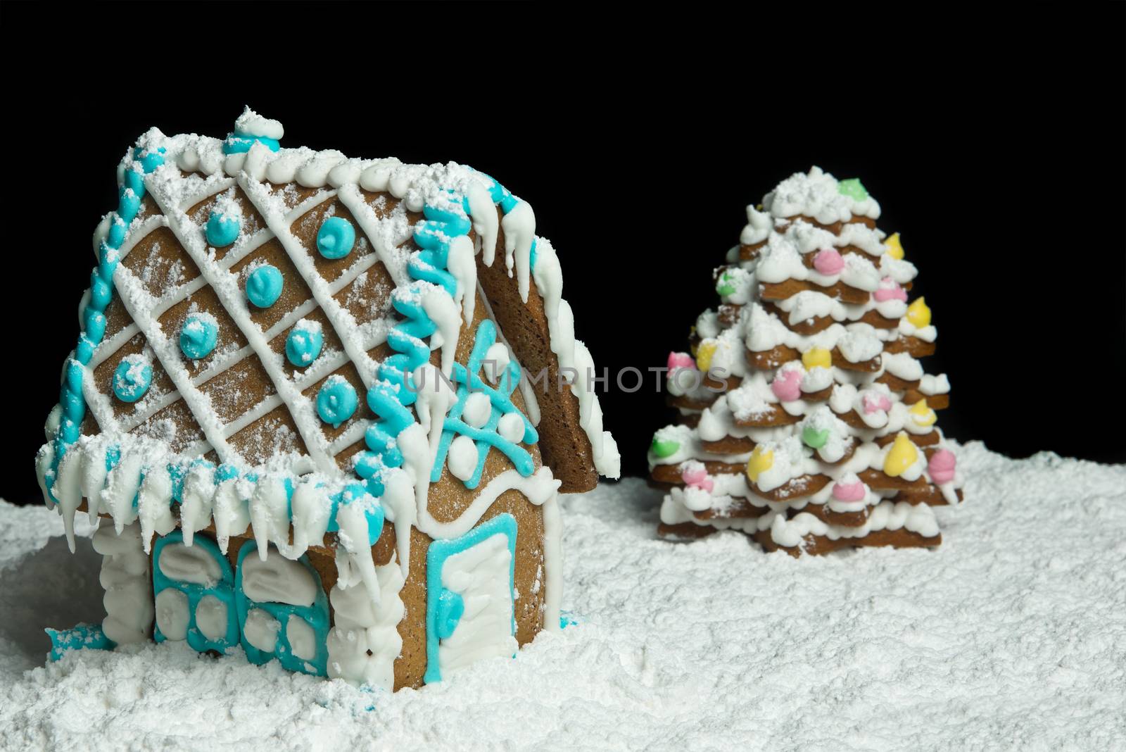 Gingerbread house and christmas tree over black background