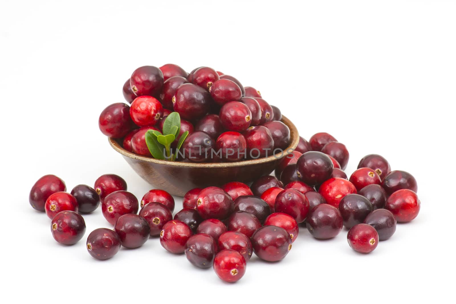 Cranberries in wooden bowl on white background.