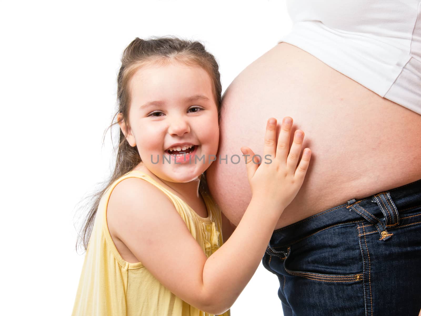 Smiling little girl holding belly of pregnant mother isolated on white