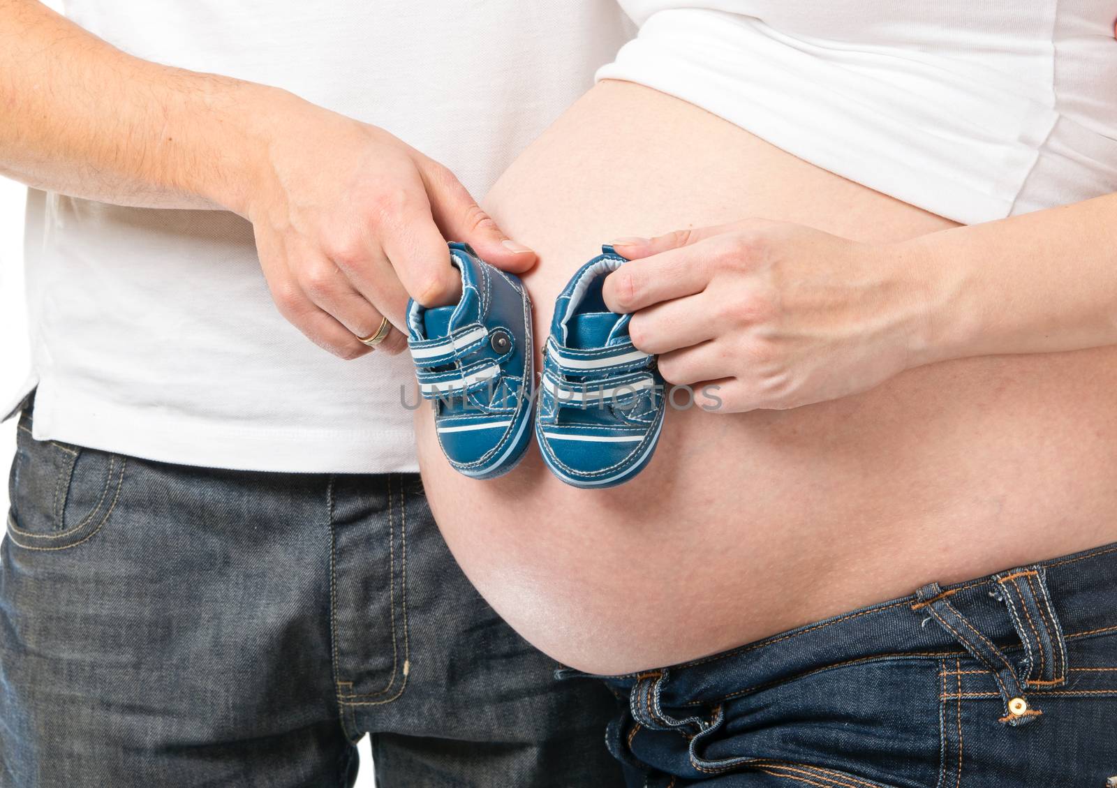 Man and pregnant woman holding small blue shoes close up