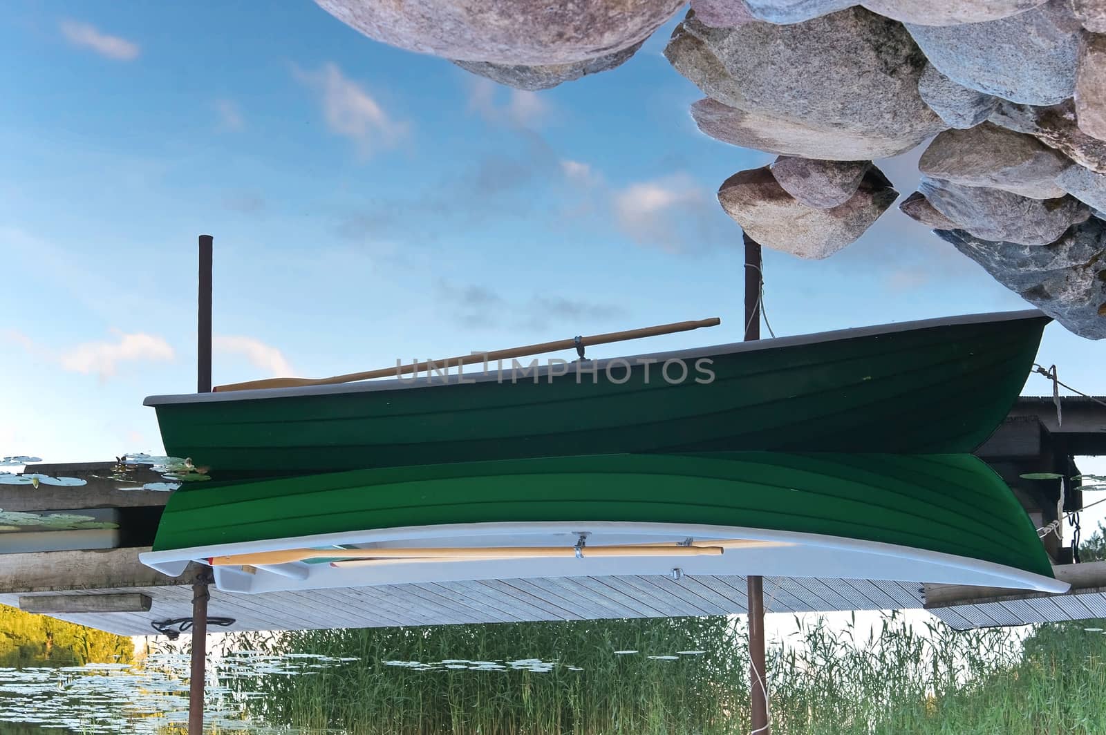 Row boat near wooden jetty. Upside down picture.