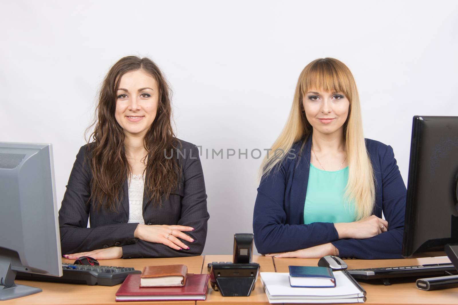 Two young pretty business woman sitting at a office table is divided into two jobs