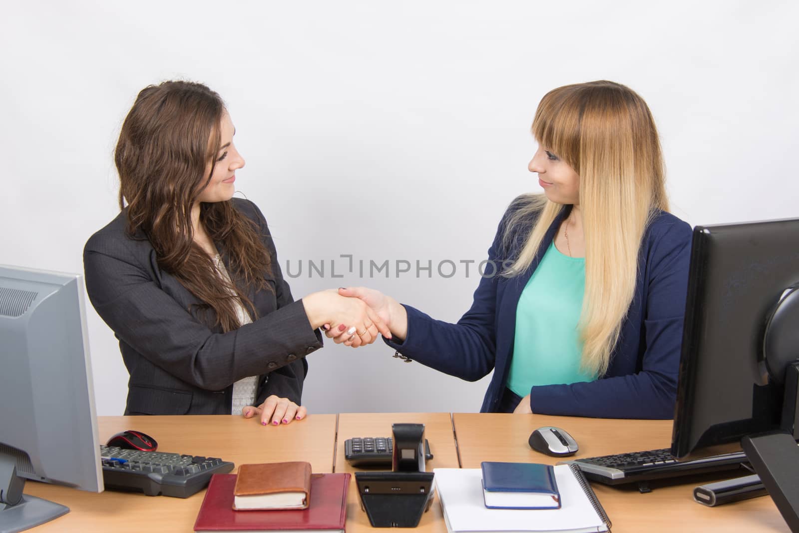 Two young pretty business woman sitting at a office table is divided into two jobs
