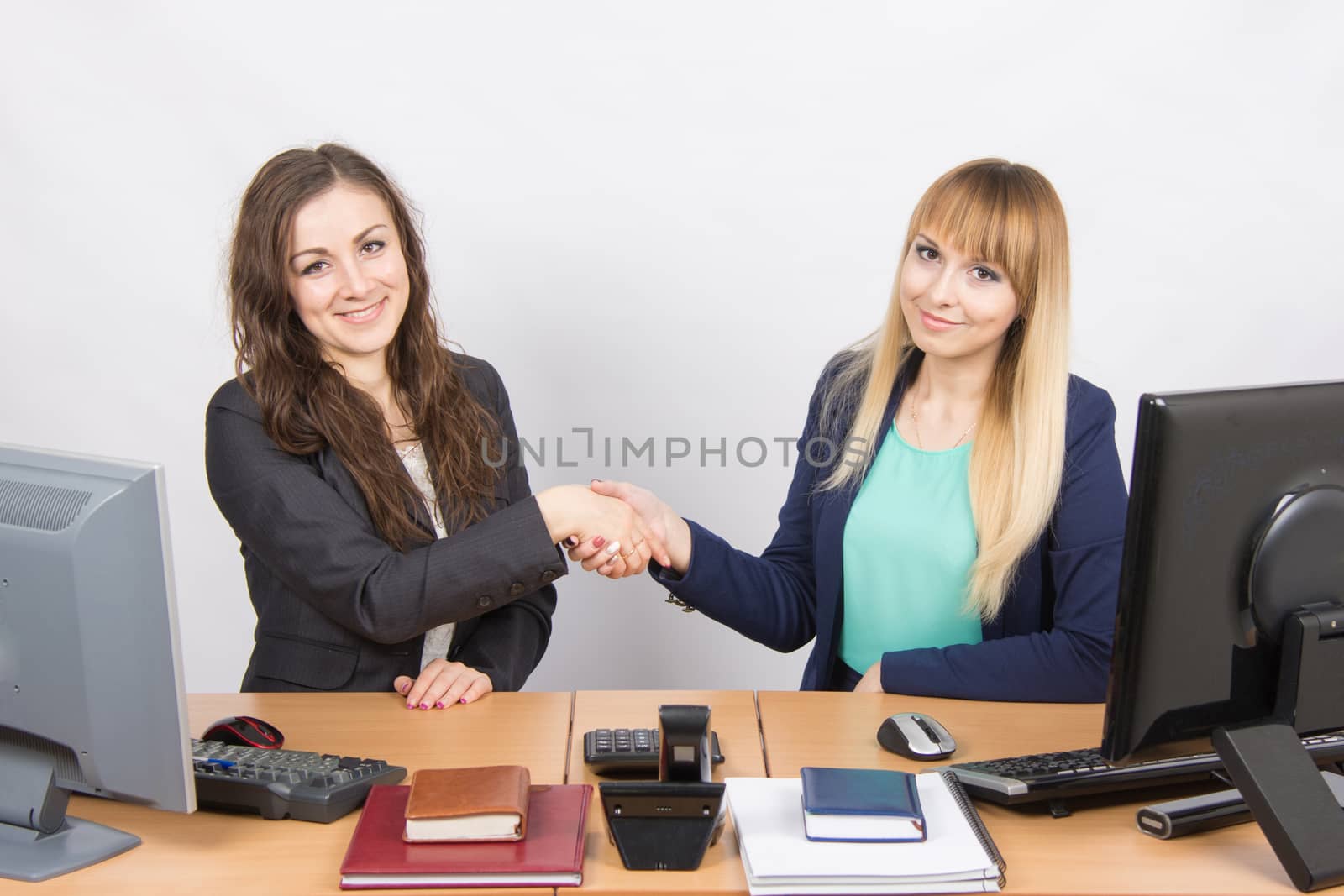 Two young pretty business woman sitting at a office table is divided into two jobs
