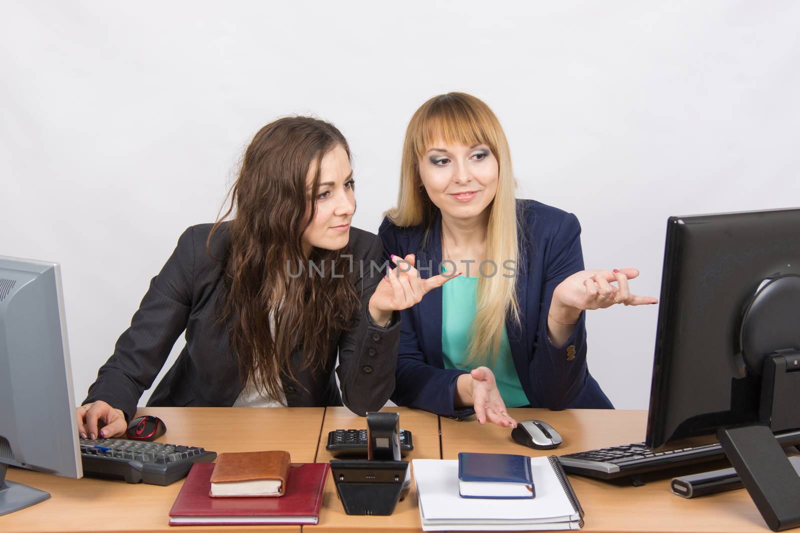 Two young pretty business woman sitting at a office table is divided into two jobs