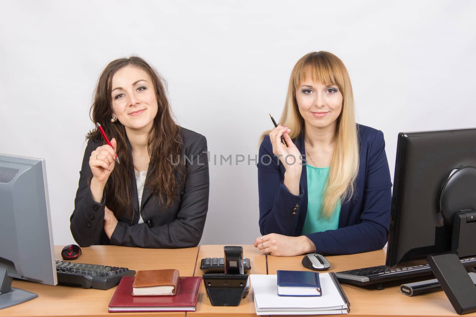 Two young pretty business woman sitting at a office table is divided into two jobs