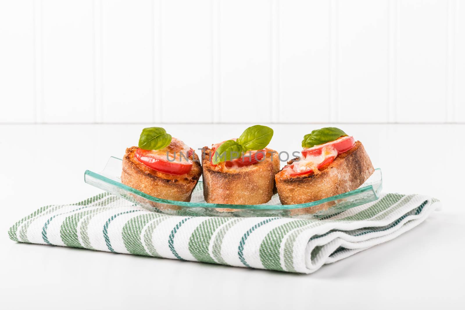 Tomato, mozzarella and basil crostini in a glass plate.  Useful for a number of food service promotional applications.