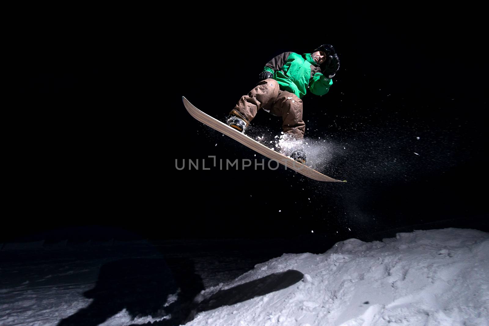 Snowboarder jumping at night