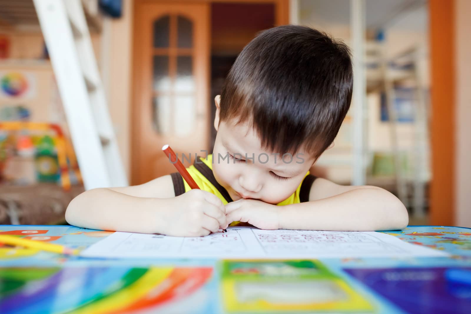 Busy little boy drawing using felt pens at home with colorful interior. by Maynagashev