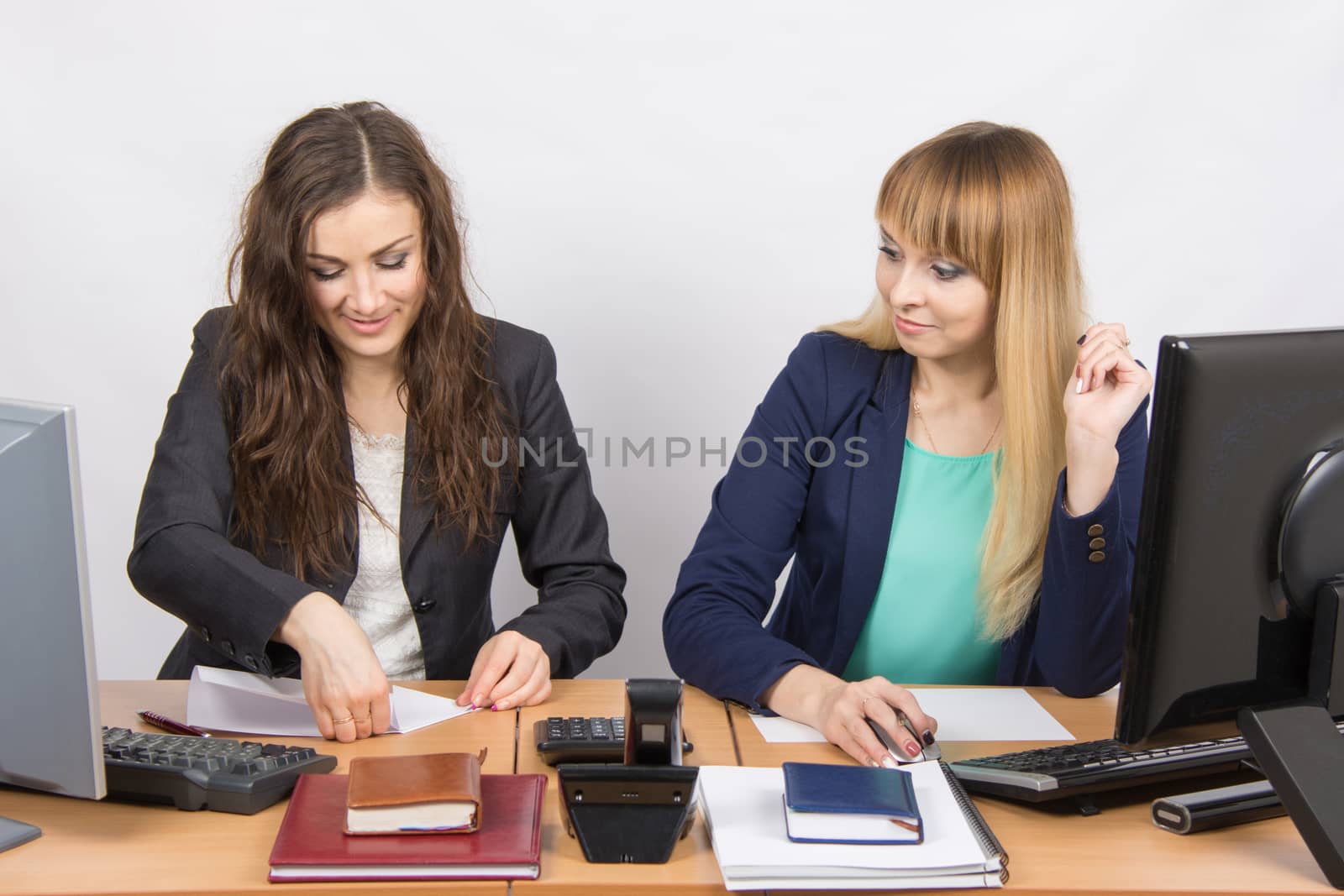 Two young pretty business woman sitting at a office table is divided into two jobs