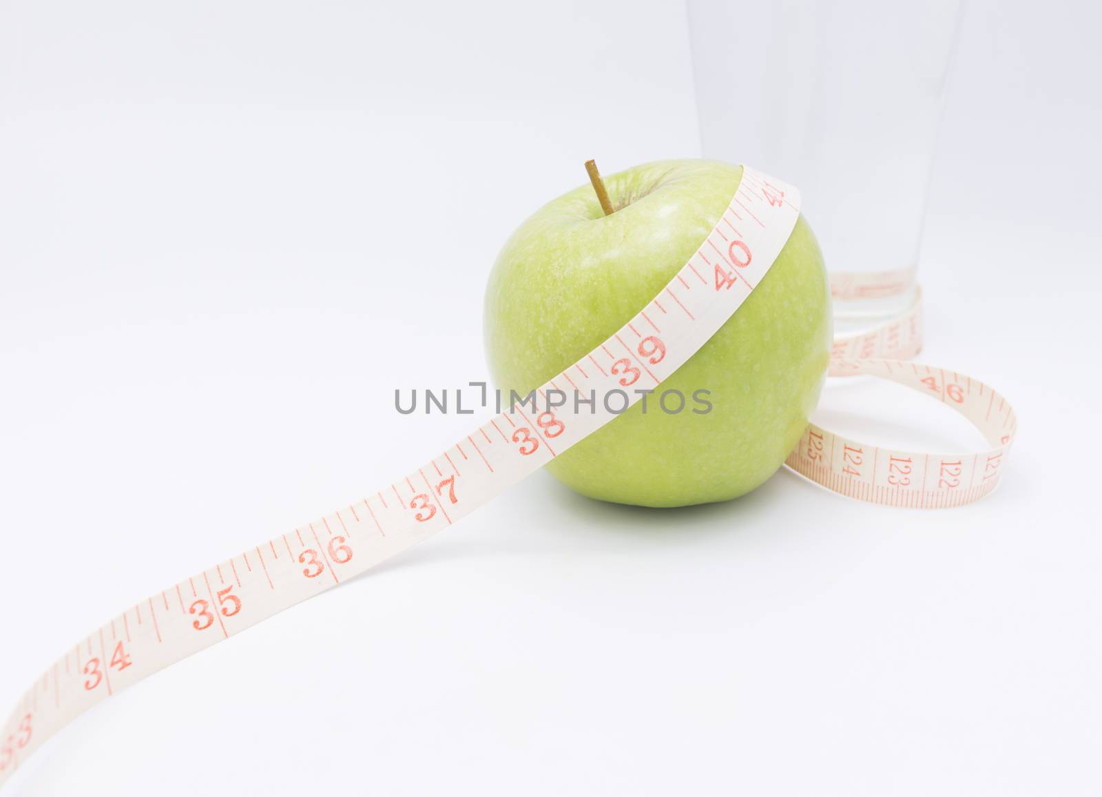 A green apple with a measuring tape wrapped around it for the concept of BMI