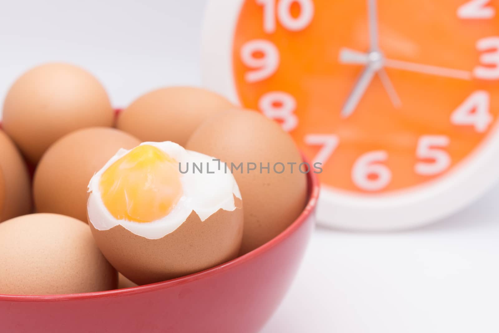 medium-boiled eggs  in red bowl with clock for morning time concept