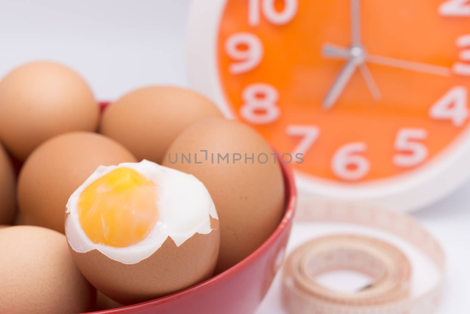 medium-boiled eggs  in red bowl with clock for morning time concept
