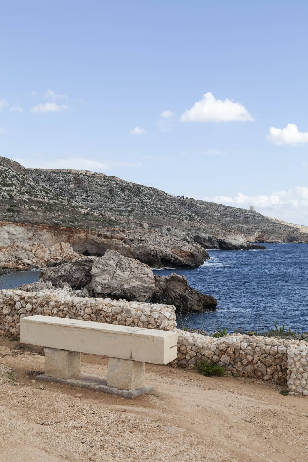 stone bench on rocky coast of  Mediterranean Sea with blue water on Malta, Europe