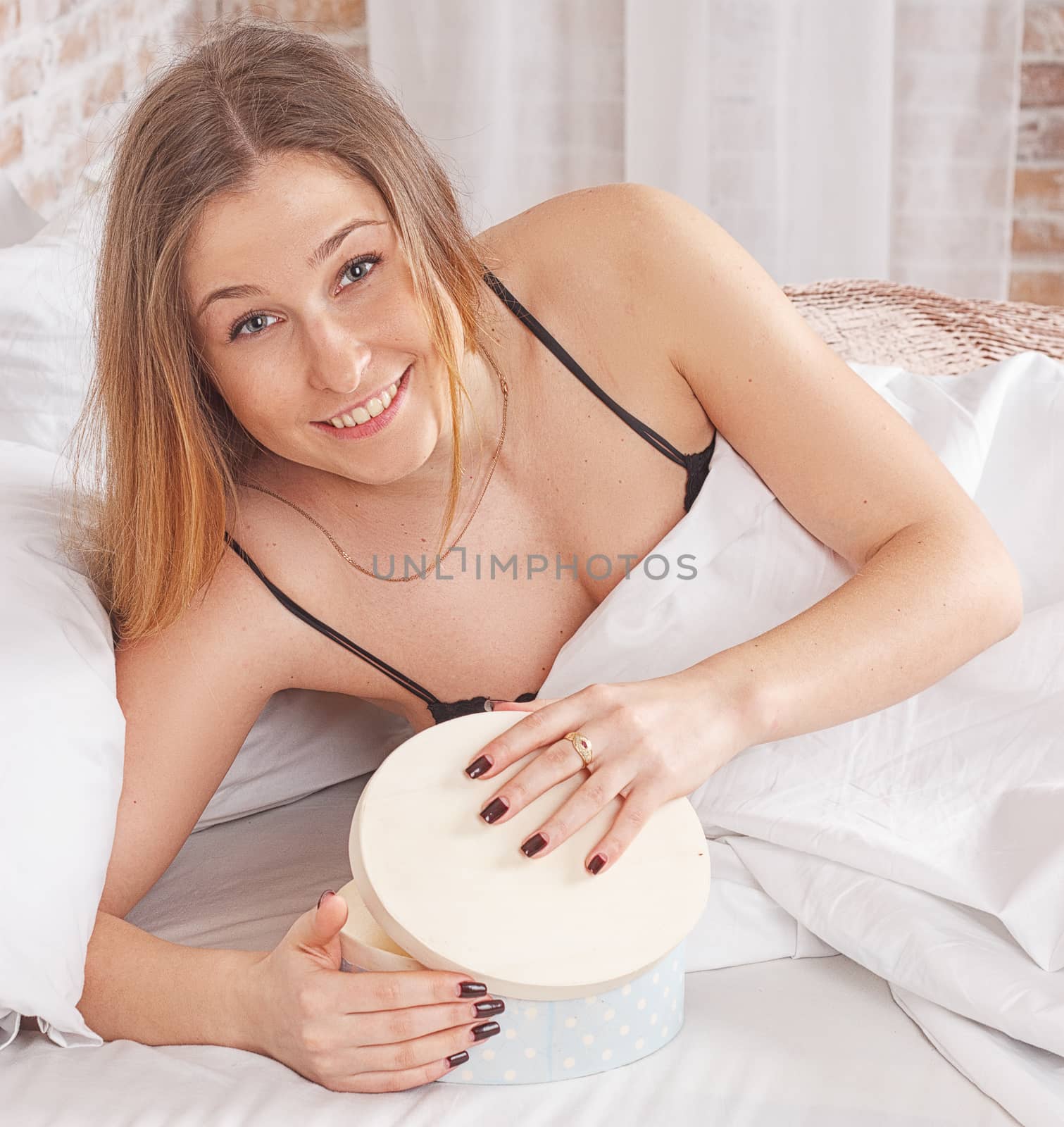 Happy woman lying on the bed and looking on the gift