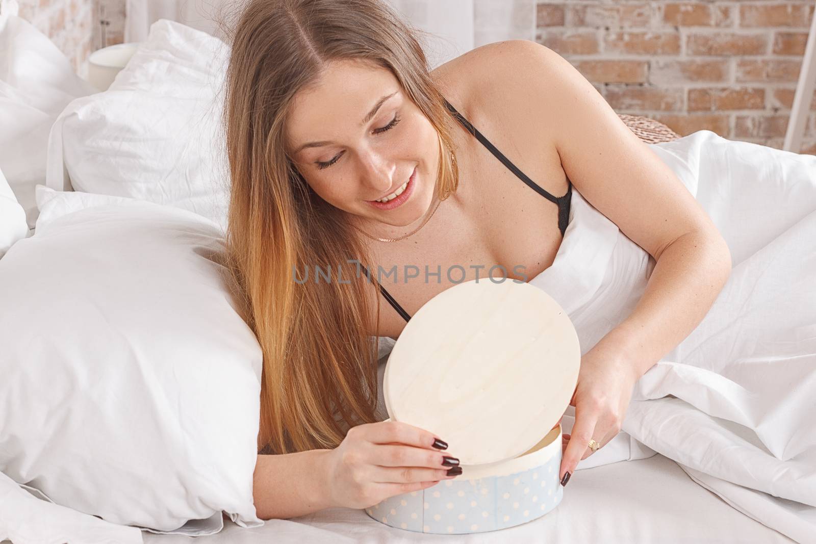 Happy woman lying on the bed and looking on the gift