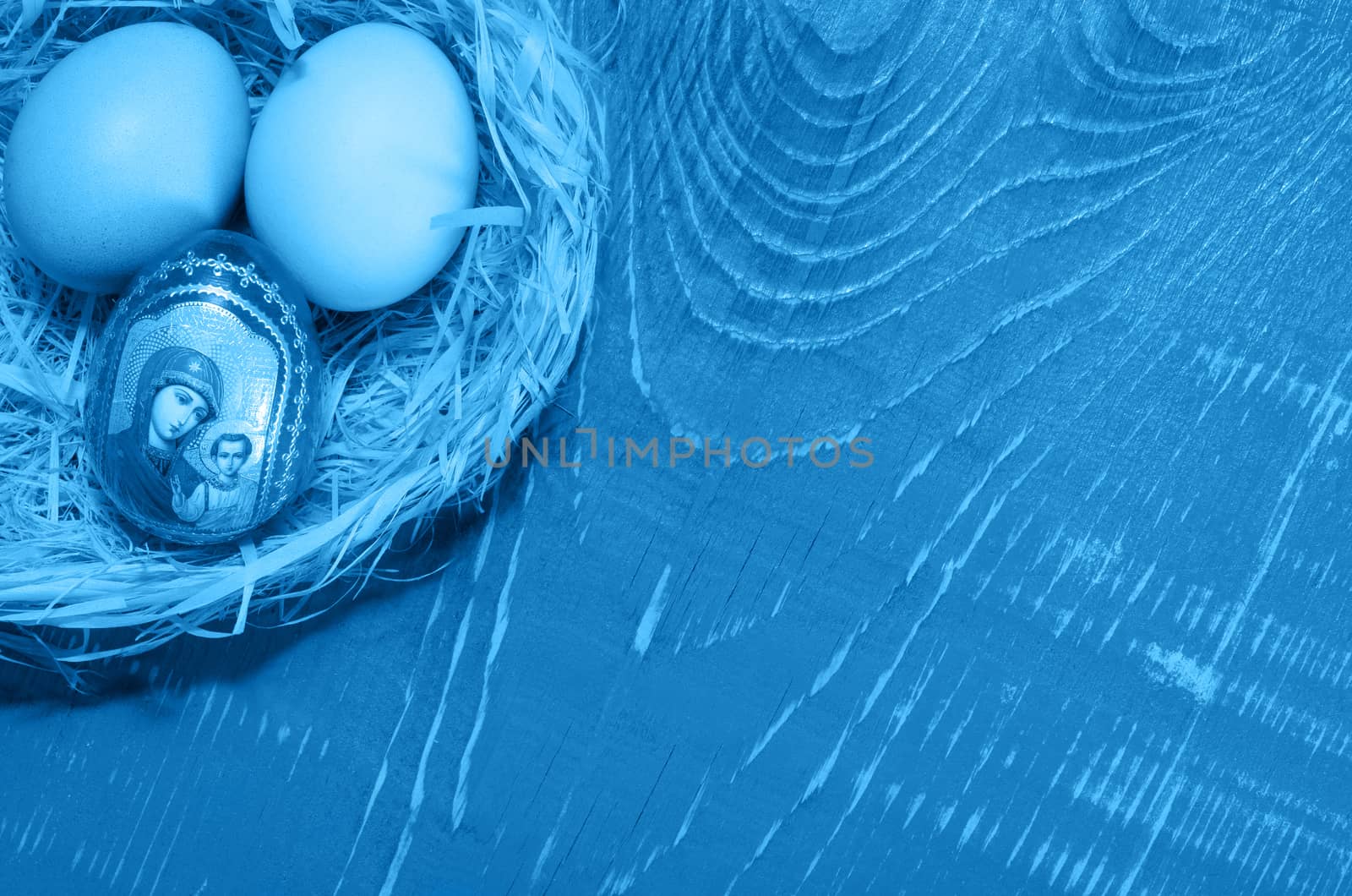 Eggs in the nest of bark, lying on a wooden background toned in blue color. On the Board, place for text.