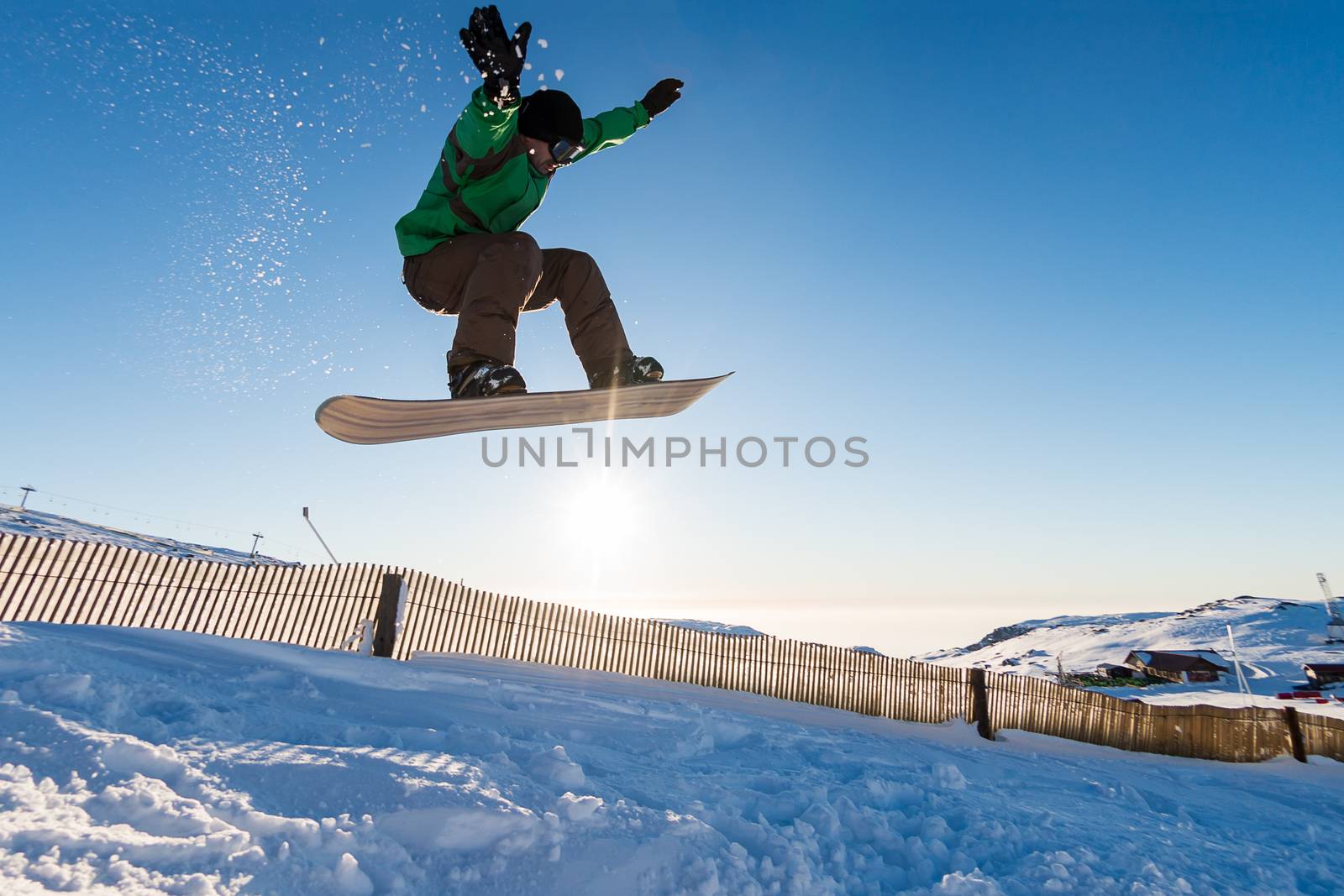 Snowboarder at jump in mountains at sunset sky.