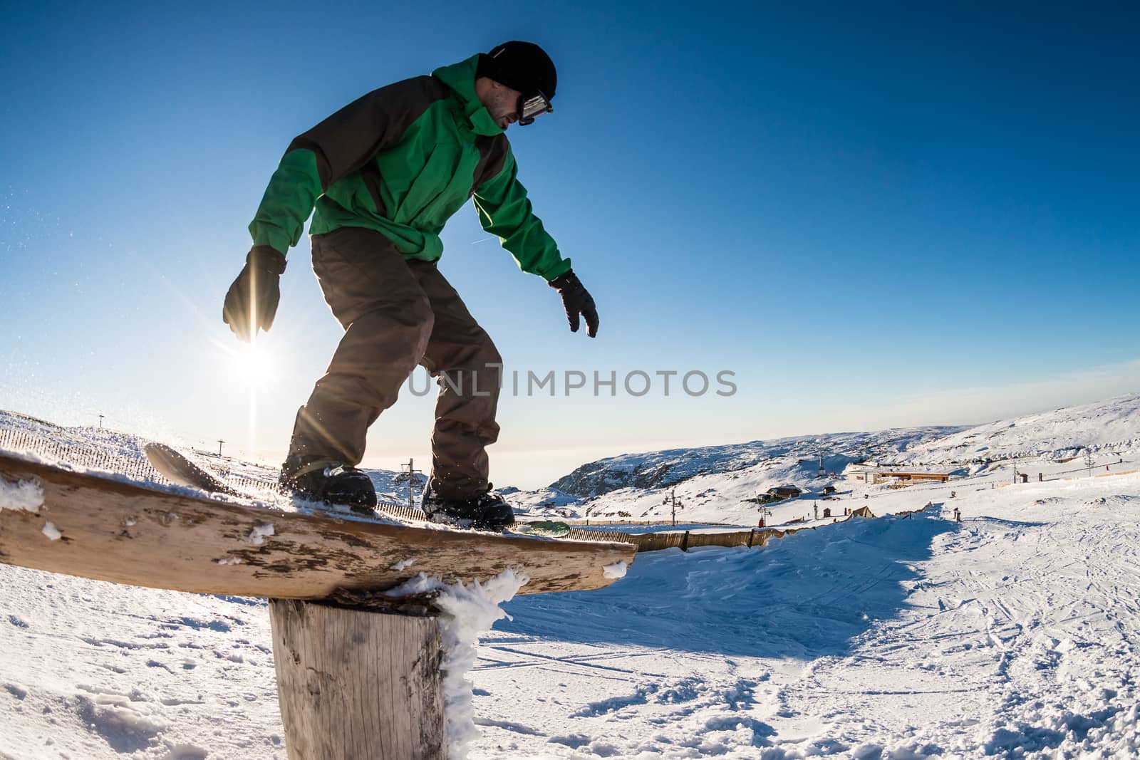 A snowboarder executes a radical slide on a rail in a snow park.