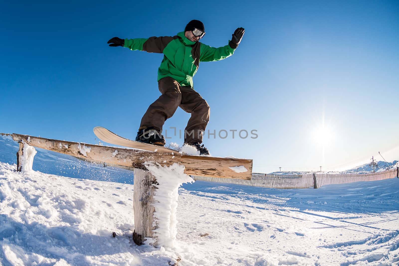 A snowboarder executes a radical slide on a rail in a snow park.