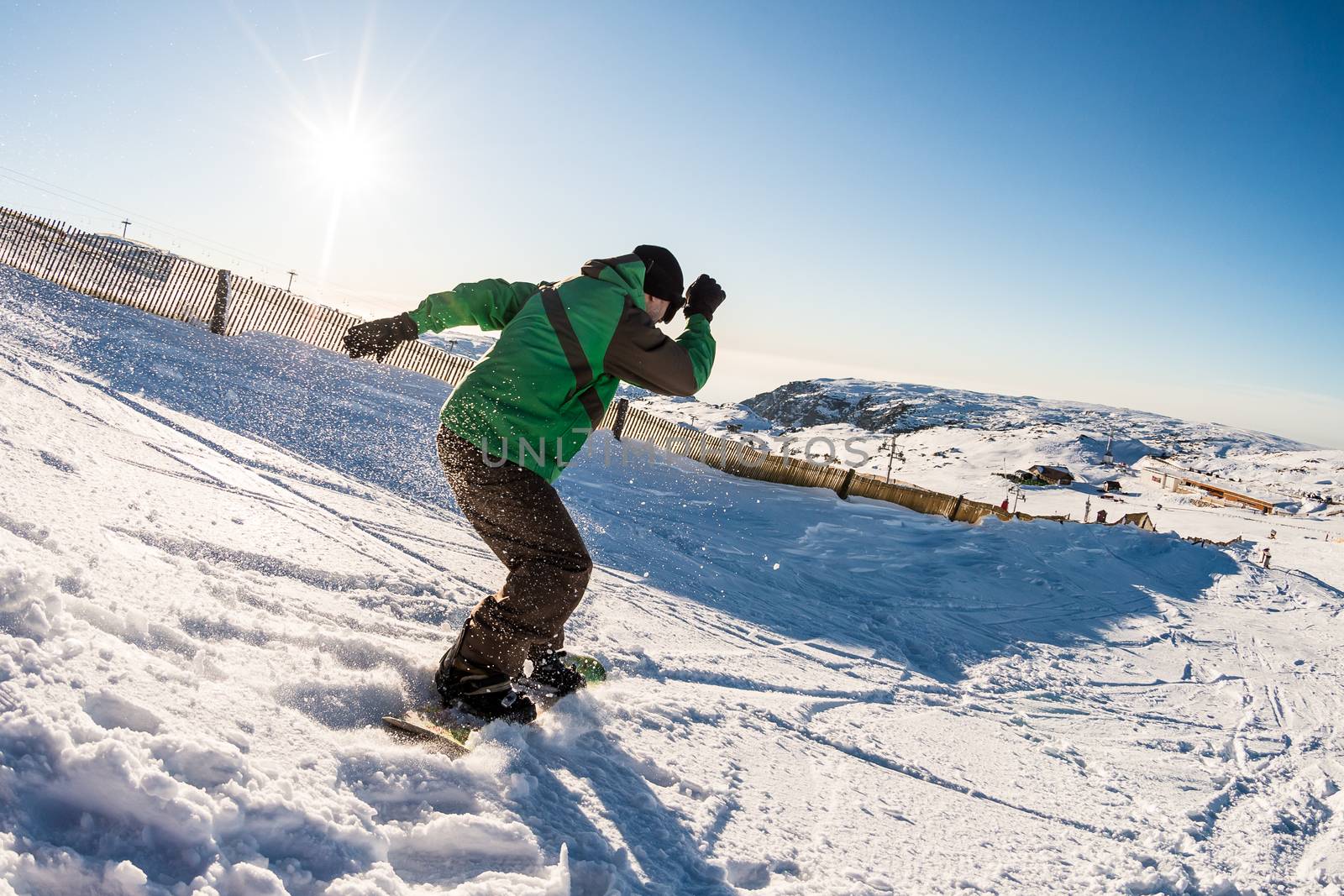 Snowboard freerider in the mountains against sun shine in blue sky.