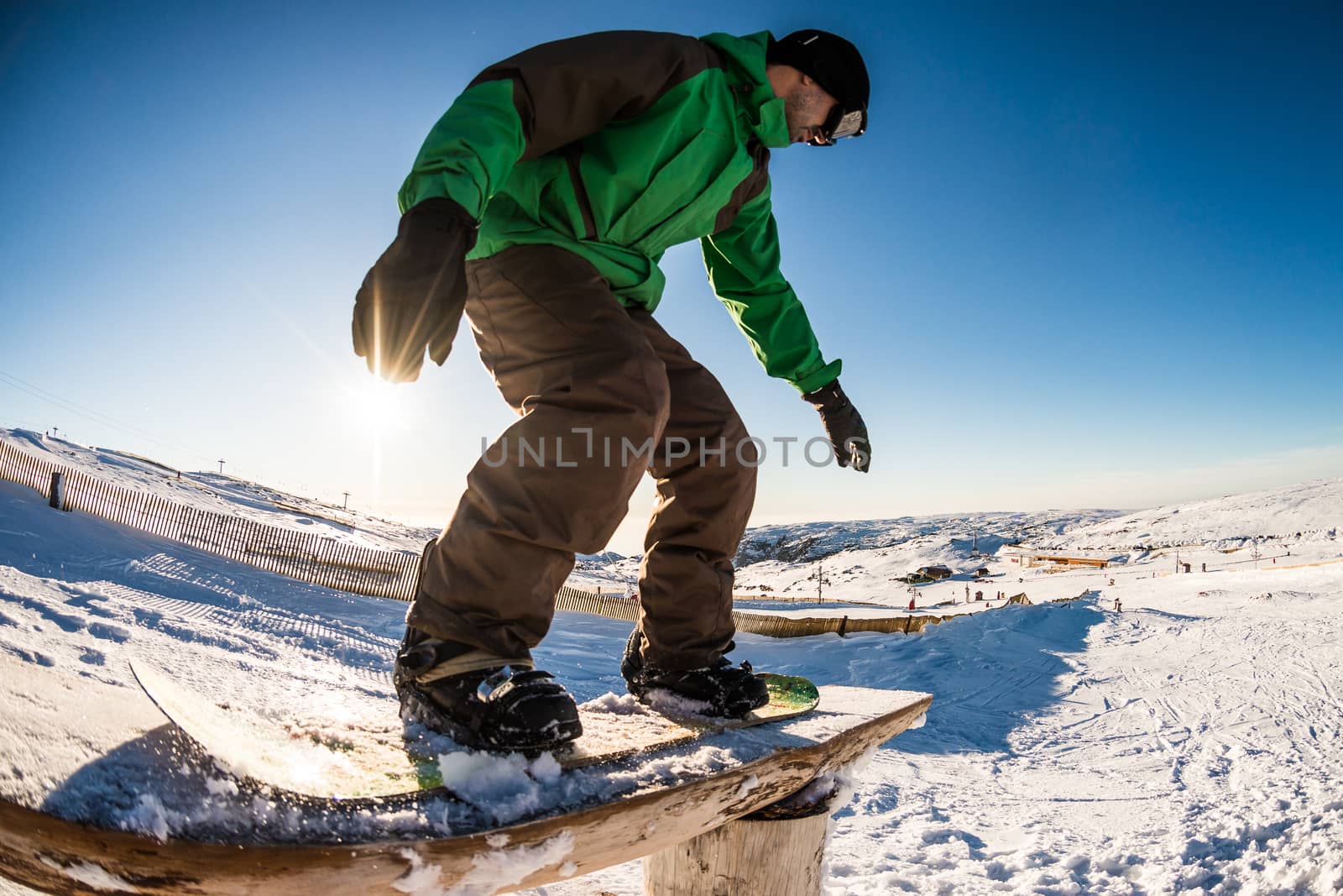 A snowboarder executes a radical slide on a rail in a snow park.