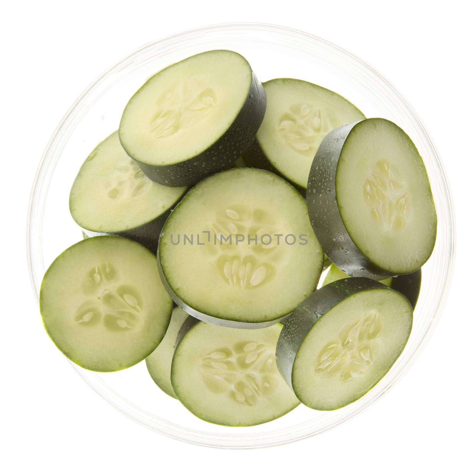Slices of fresh cucumbers in a bowl and isolated on white.