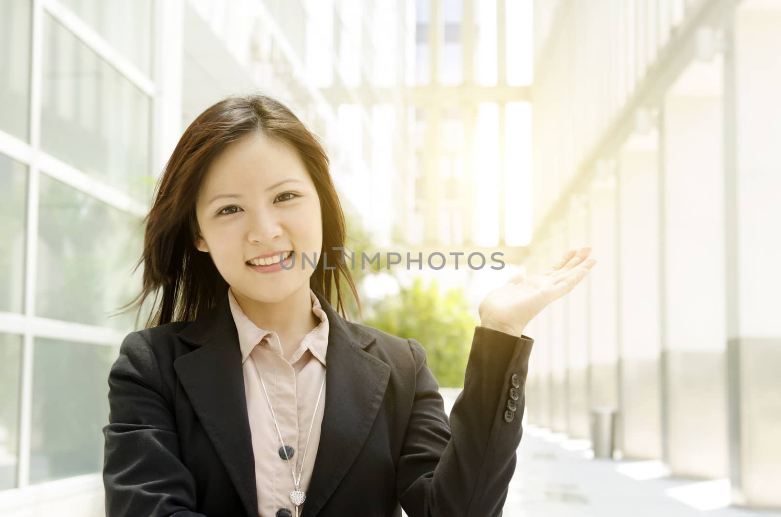 Young Asian business woman hand showing somethings, at an office environment, natural golden sunlight at background.
