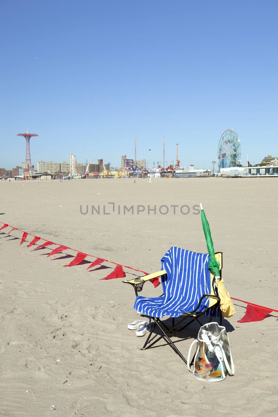 empty chair with towel on sunny coney island beach waits for sitter  to return