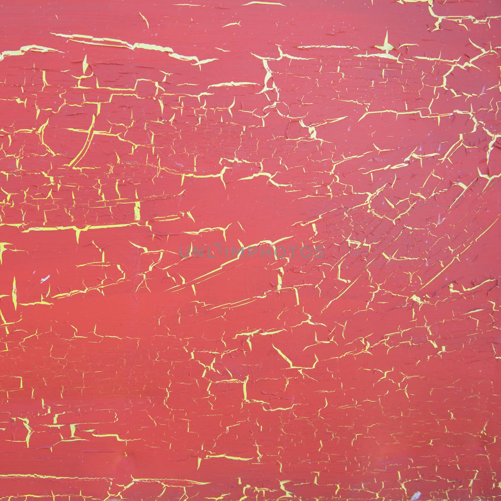 square surface with red cracked paint on yellow background