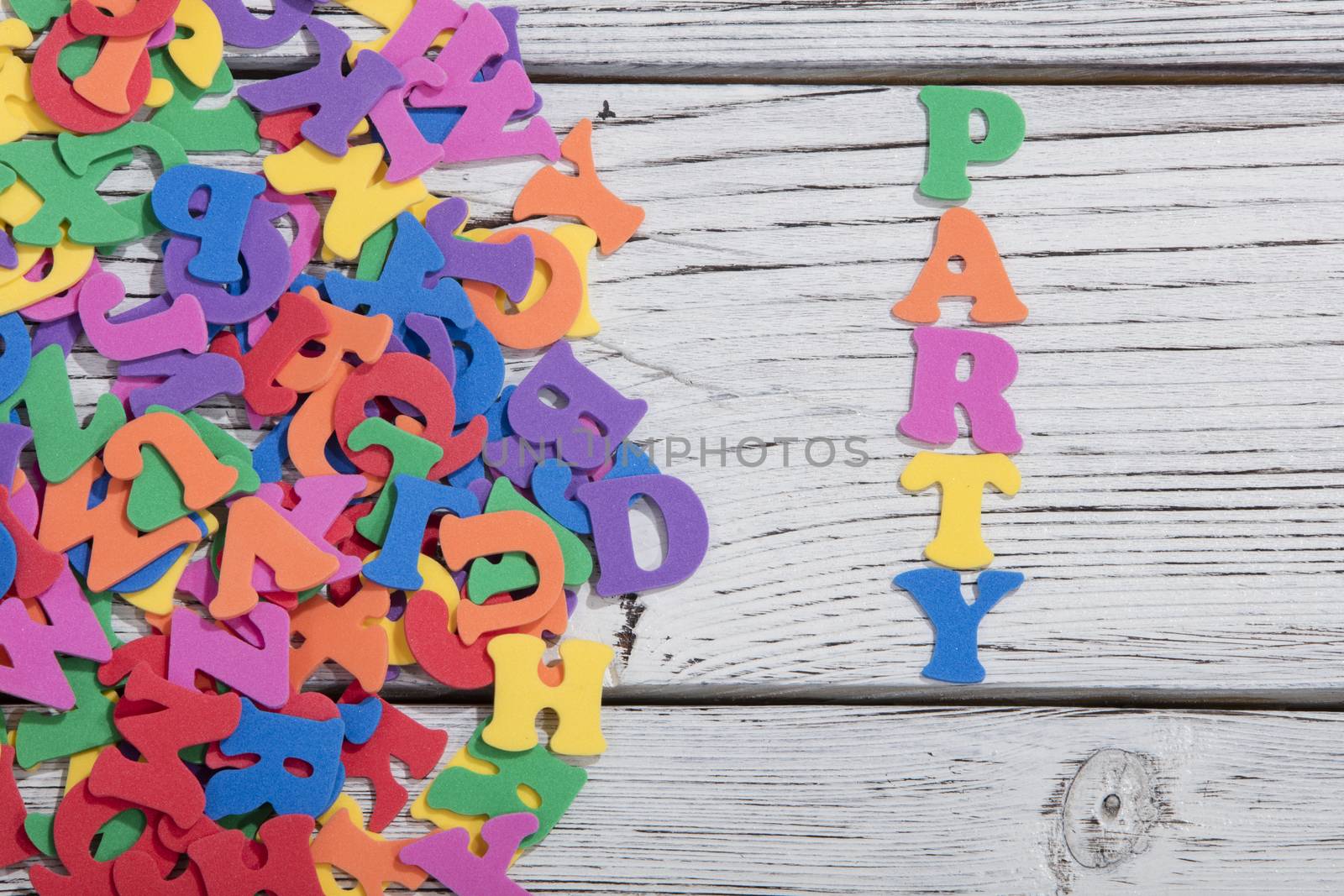 the colorful words party made with colorful letters over white wooden board by senkaya