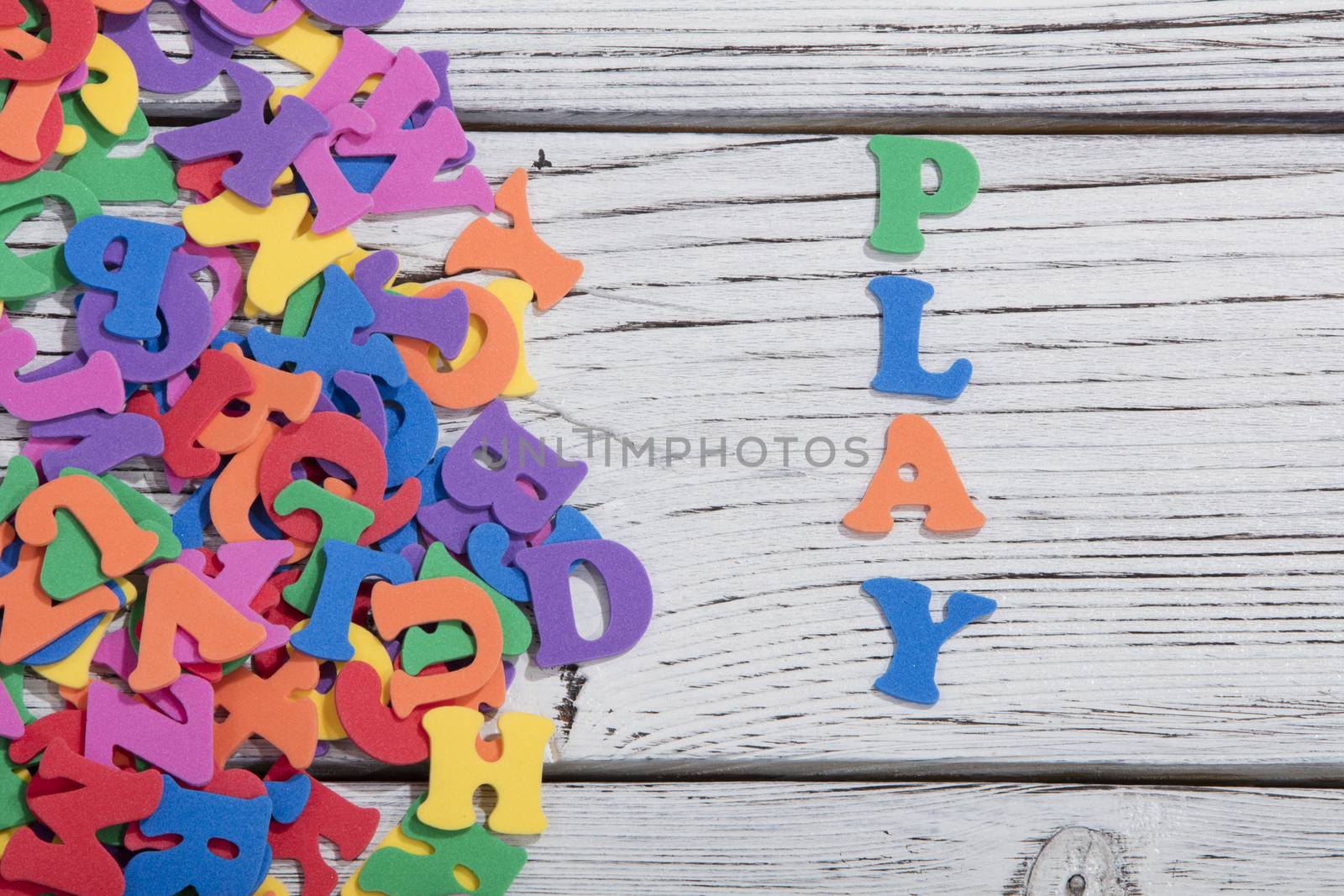 the colorful words play made with colorful letters over white wooden board by senkaya
