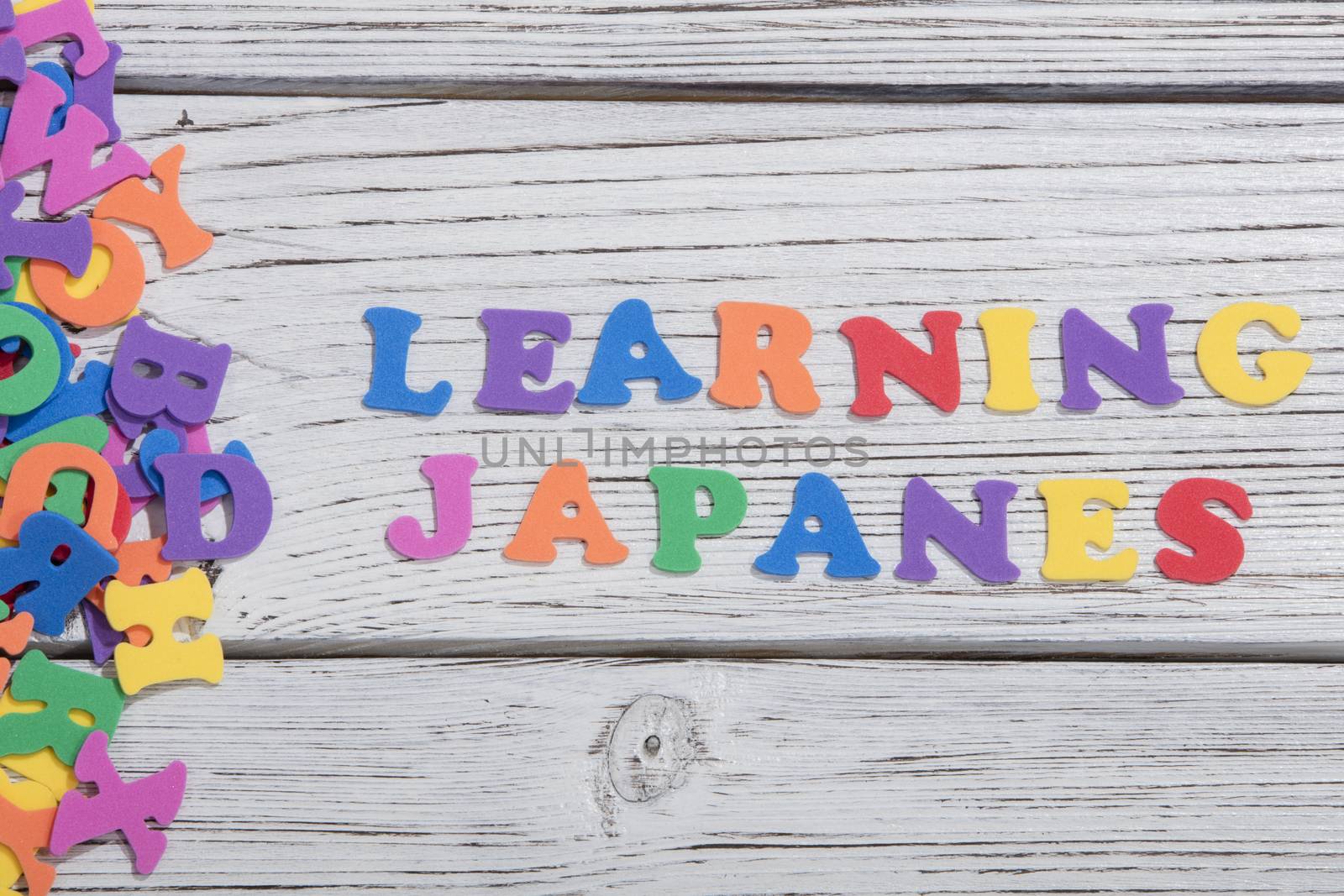 the colorful words japanes made with colorful letters over white wooden board by senkaya