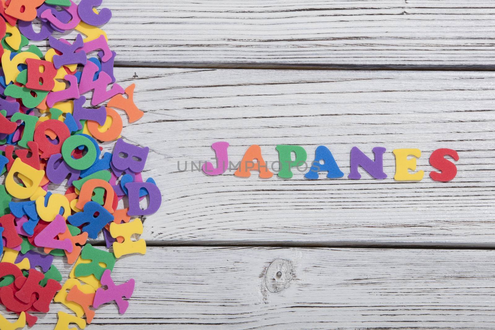 the colorful words japanes made with colorful letters over white wooden board by senkaya