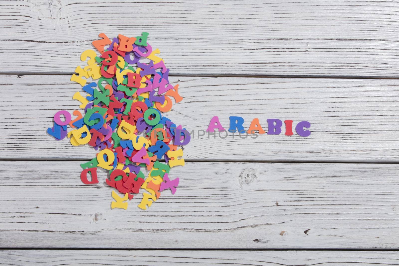 the colorful words arabic made with colorful letters over white wooden board by senkaya