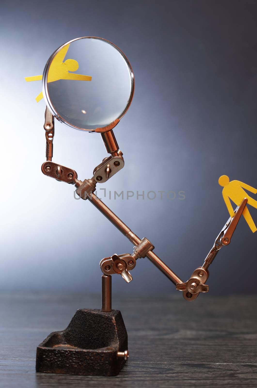 Human rights concept. Yellow paper man in metal clamping device under magnifying glass