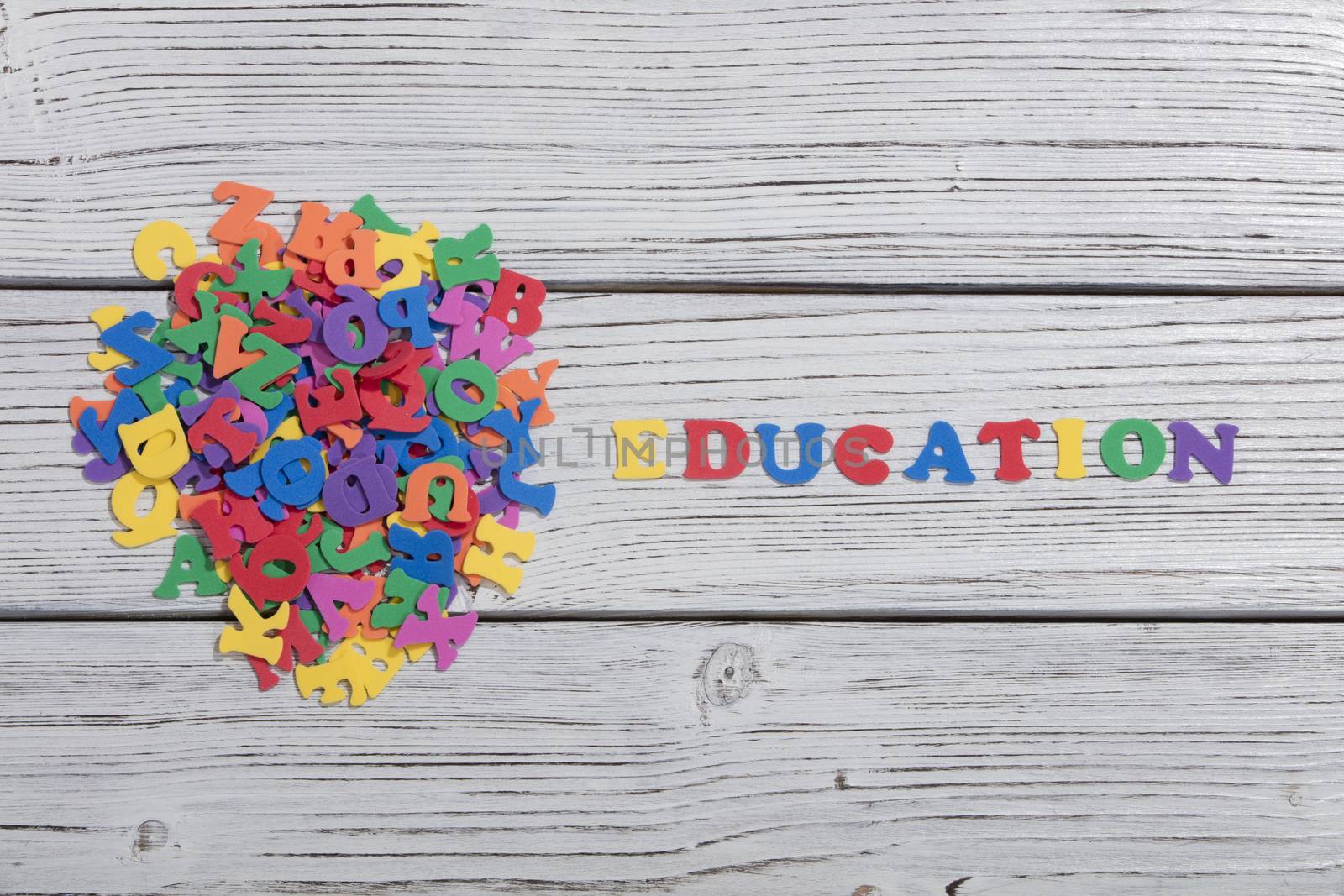 the colorful words education made with colorful letters over white wooden board by senkaya