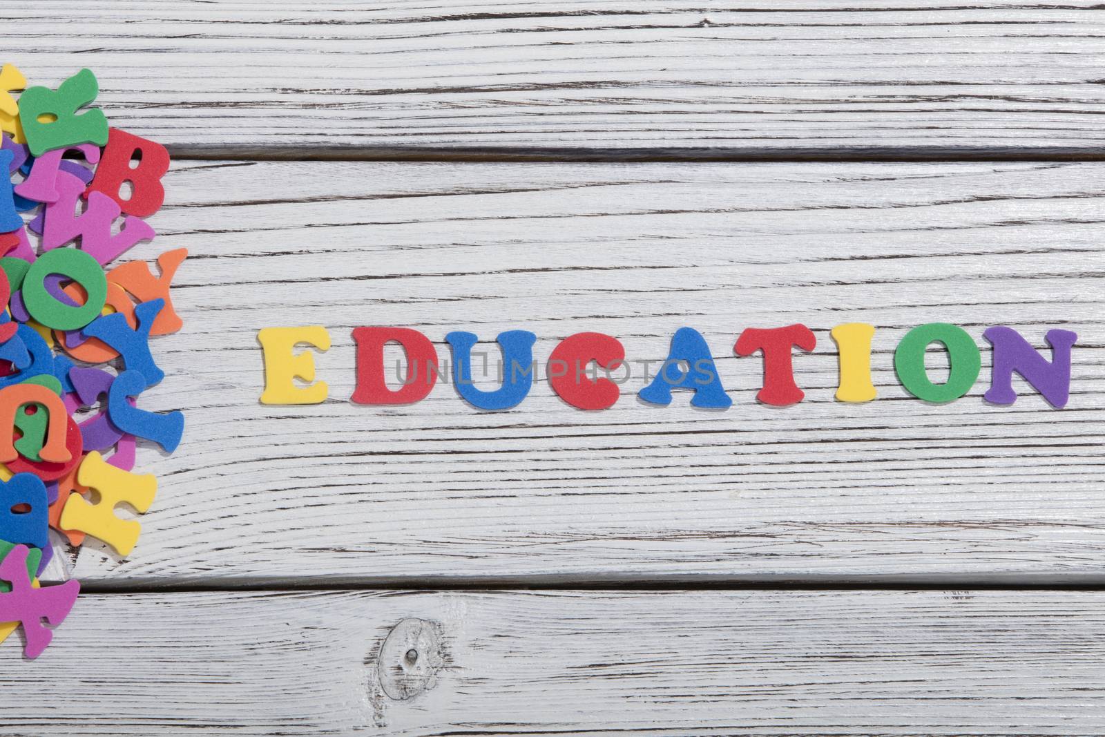 the colorful words education made with colorful letters over white wooden board by senkaya