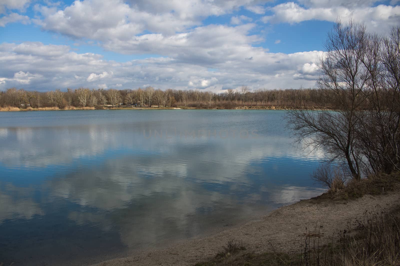 Lake in Ivanka pri Dunaji, Slovakia. Cloudy sky, reflected in the water. Forest on the horizon.