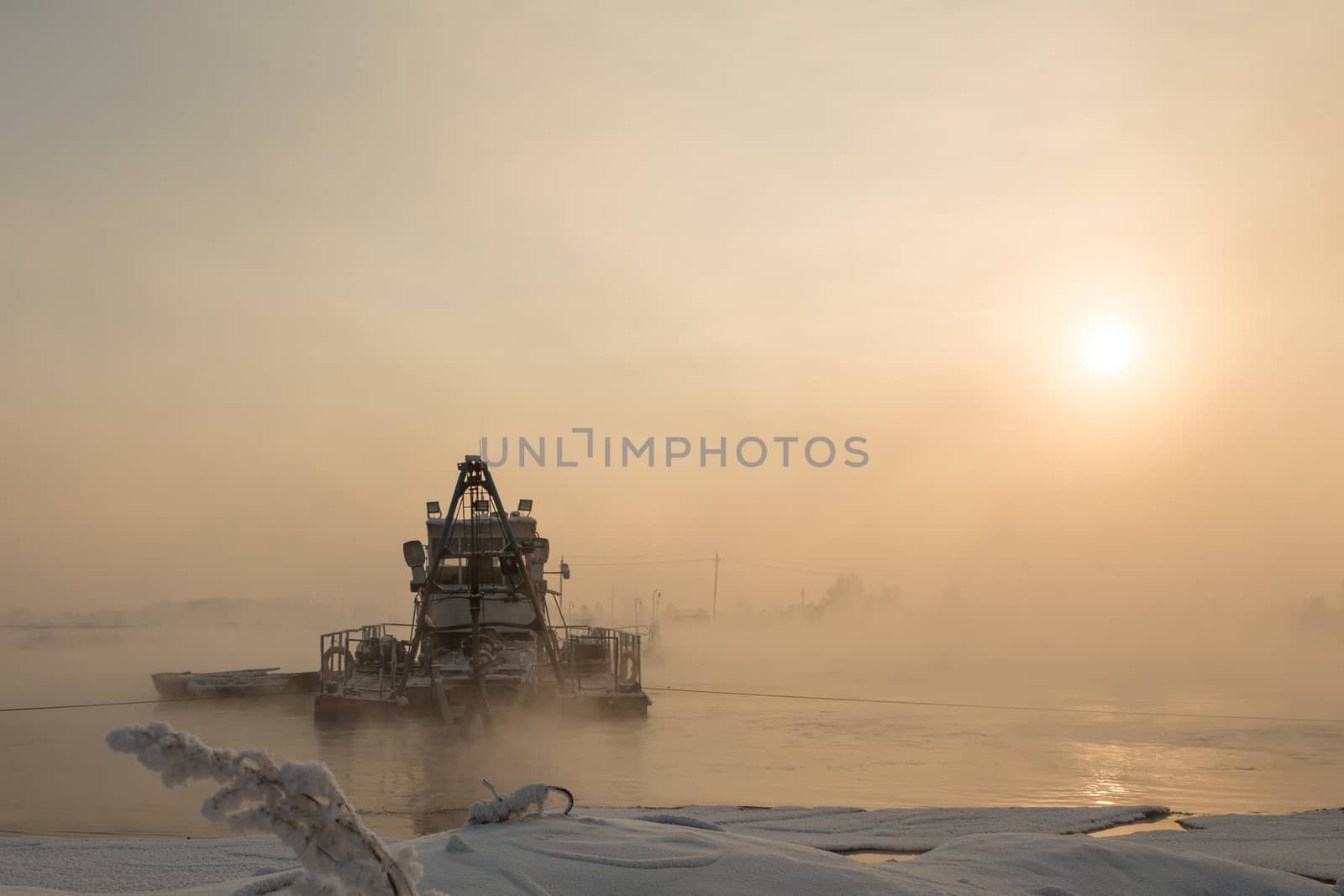 a dredger boat in winter mist at sunset